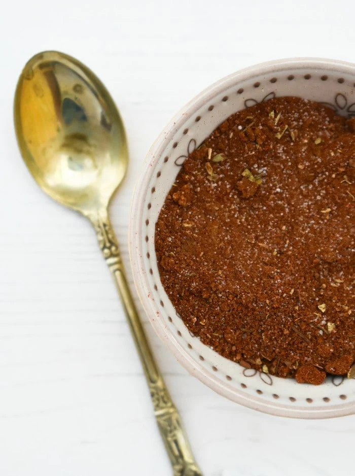 Fajita Seasoning in a small white bowl next to a small gold spoon