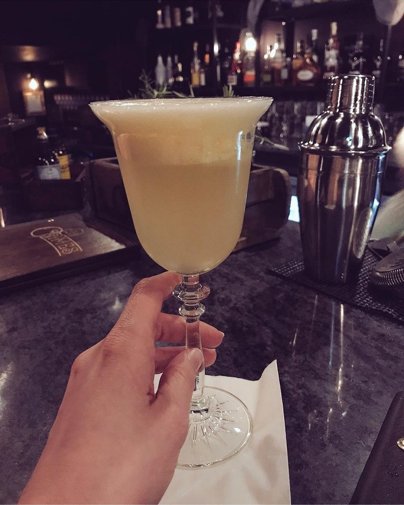 Hand holding the stem of a cocktail glass in 21 Crimes bar Aberdeen