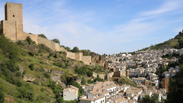 Castillo en lo alto de la montaña y el pueblo abajo de casas blancas.
