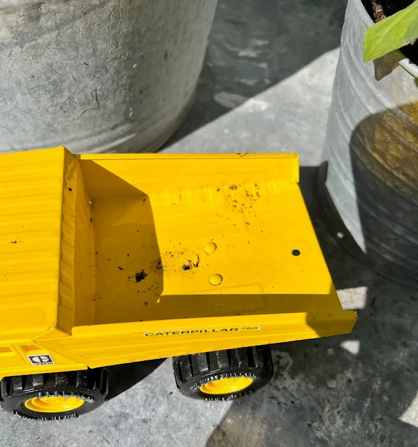 Photo of a toy dump truck with drainage holes on the bottom.
