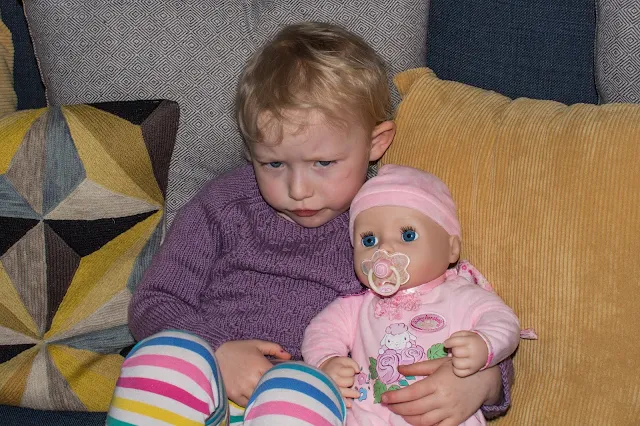 Toddler cuddling baby annabell while reviewing her