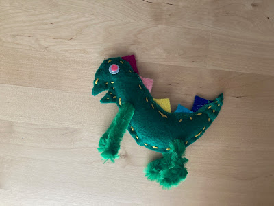 Green stuffed dinosaur with pink eyes