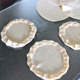 Crimping the edges of empanada rounds to make mini pizzas