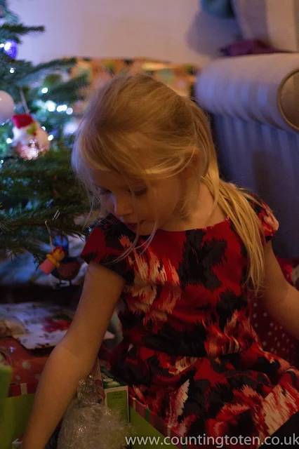 A blonde 4 year old in front of a tree and presents