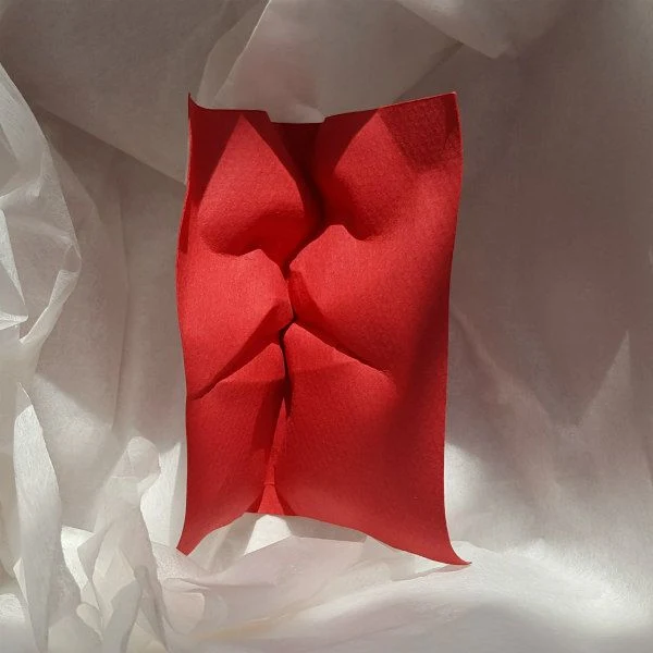 red paper sculpture details two faces kissing