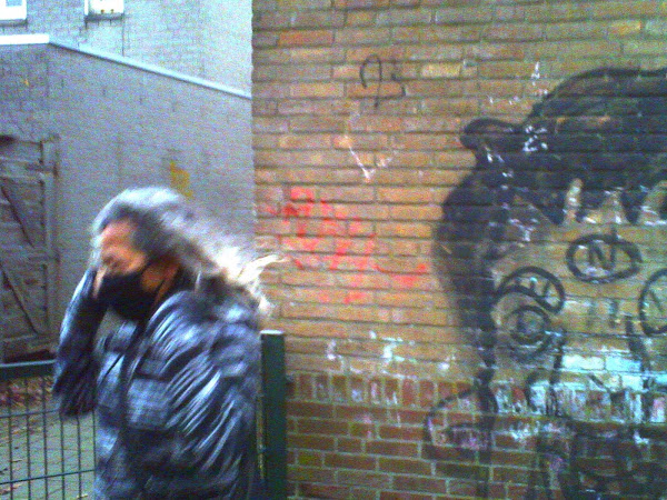 Vrouw met mondkapje bij Nicker-graffiti