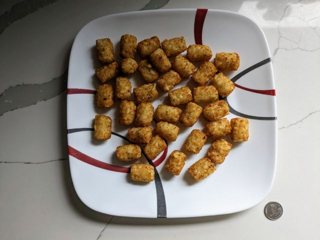 A plate of Trader Joe's Potato Tots next to a quarter.