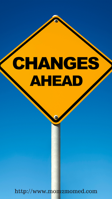 Upcoming changes to Mom2MomEd with yellow and black "changes ahead" street sign against a bright blue background