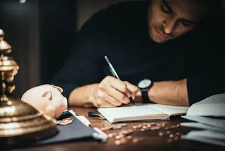 A person writing notes in a book with the heading “Money Routine”