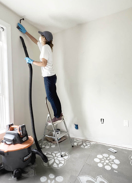 Cristina garay cleaning the wall while sanding rough spots