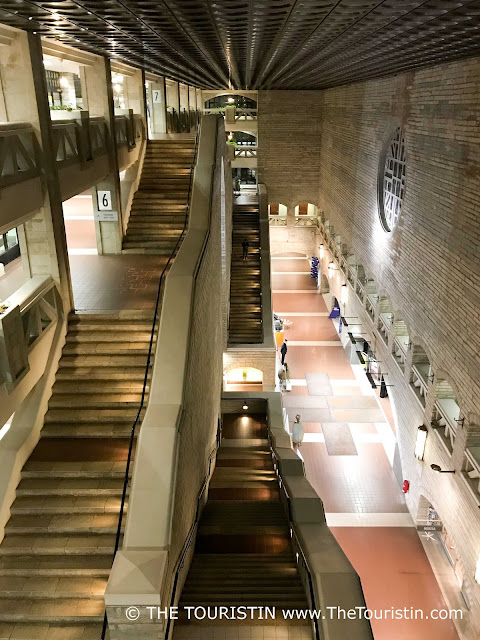 Two giant staircases in a tall hall in brutalist architecture style.