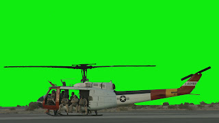 A Huey Helicopterin on the ground with crew in doorway against a green background