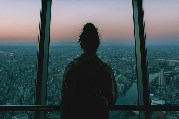 Una mujer observa la ciudad desde lo alto de un rascacielos.