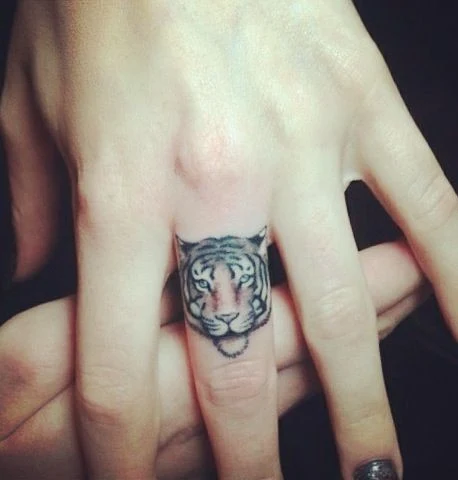 chica con el dedo medio tatuado con un tigre de bengala