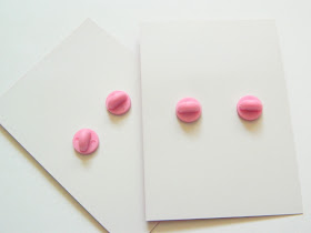 A photo showing the backs of two pin badges, they are made of smooth, pink rubber