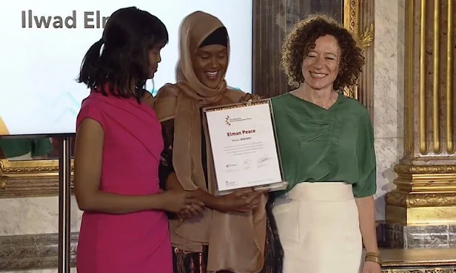 Queen Mathilde wore a red silk blouse and pattern midi skirt. Elman Peace of Somalia and King Baudouin Foundation