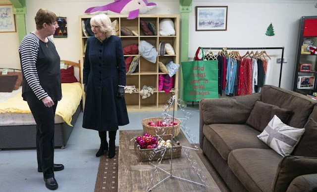 Queen Camilla wore a navy blue wool midi coat and black suede boots. The Queen visited the Emmaus boutique