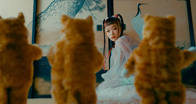 A woman looks at three standing orange cats.