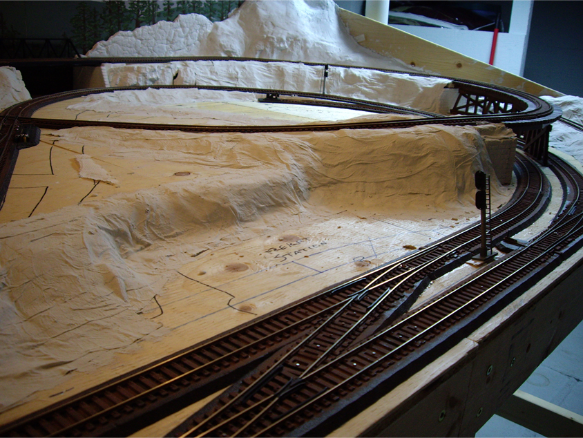 Paper towel strips soaked in plaster being applied on top of cardboard strips to form hard shell terrain