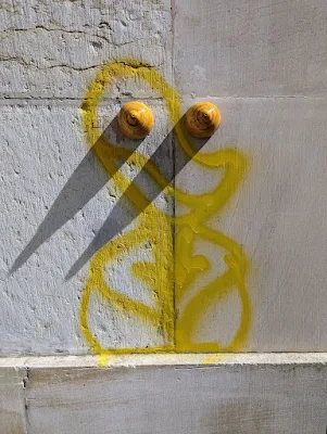 Street art painted in yellow featuring a suggestive outline of a woman's body