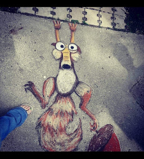 A large sidewalk chalk drawing of the squirrel and acorn from the animated film Ice Age.