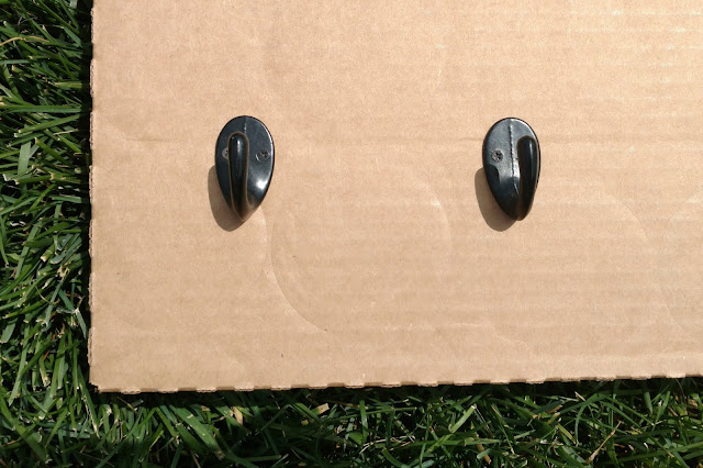 Screw hooks into a piece of cardboard before you spray them to keep them from moving around.