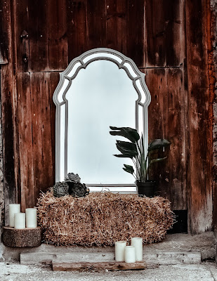 Decoracion exterior para una boda invernal con espejo, velas, balas de heno y piñas