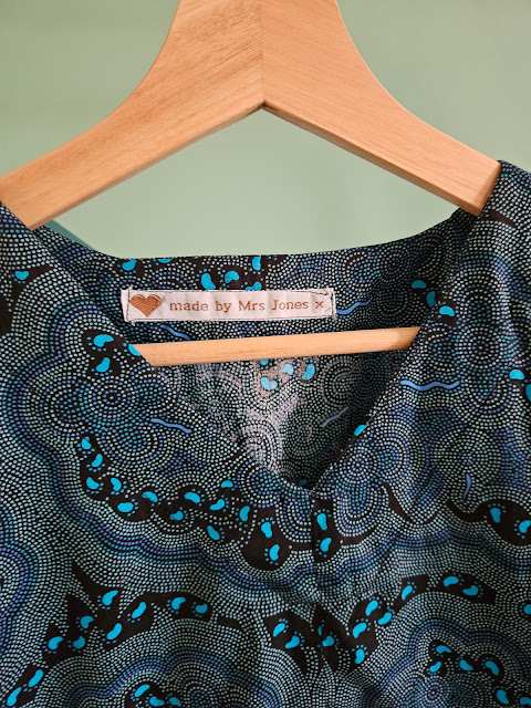 Wooden hanger and top of bodice of the teal version of the Charlie Caftan dress showing the Made by Mrs Jones label