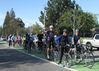 Group of cyclists stopped in a green bike lane, waiting for a green light, Cupertino, California.