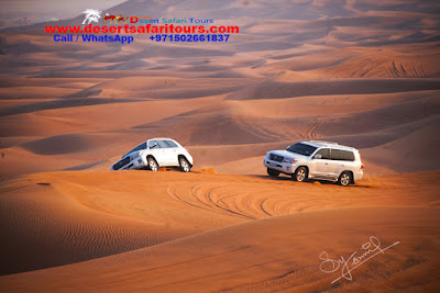 Two white color cars driving on the desert sand dunes