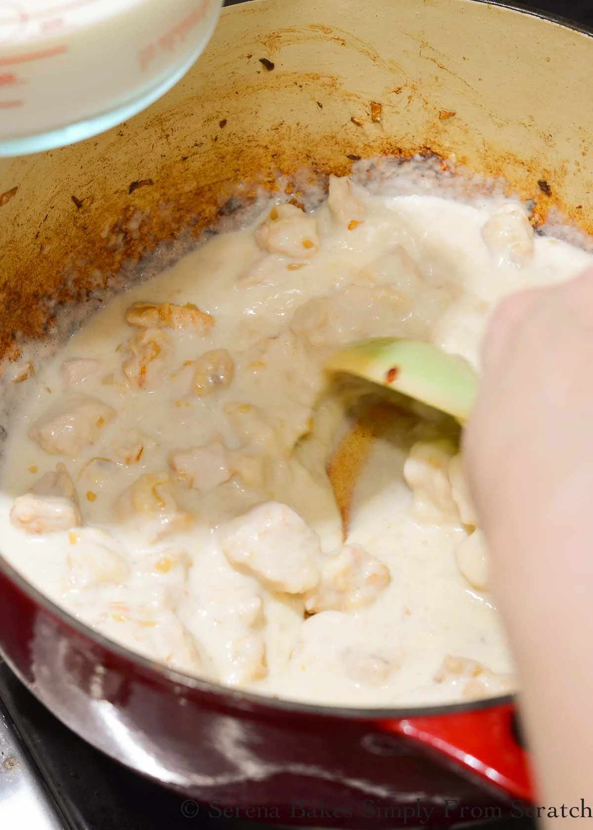 Milk being stirred in chicken and flour mixture.