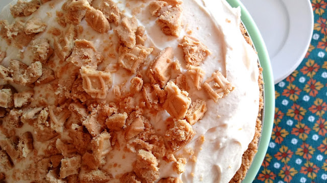 Peanut Butter Banana Cream Pie sitting on a cake stand with a floral linen background