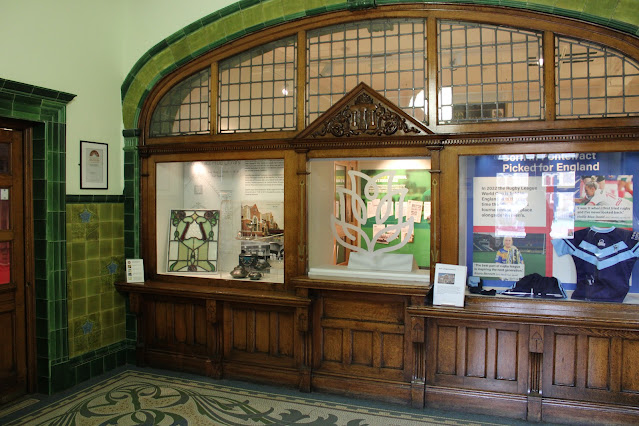 The entrance foyer at Pontefract Museum, an art nouveau building with green tiled walls, archways and a mosaic tiled floor