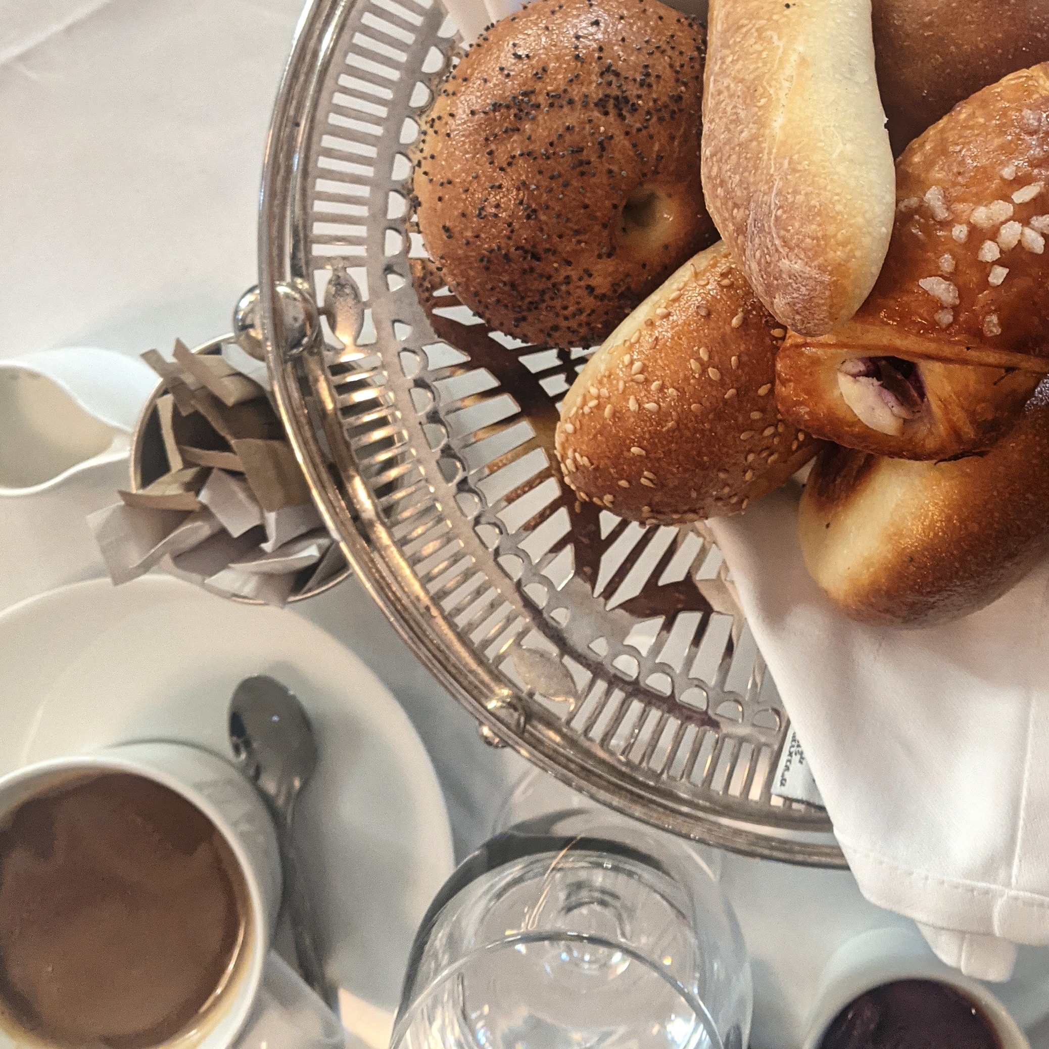 cup of americano and silver tray filled with bread and pastries at hotel montefiore in tel aviv