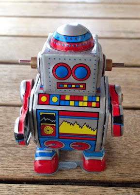 A grey tinplate robot with red, yellow and blue decoration. He walks when his mechanism is wound up using a key in his side.