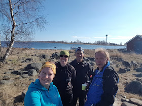 Aurinkoisella rannalla hymyilevät kolme meribiologia ja matkailuyrittäjä. 