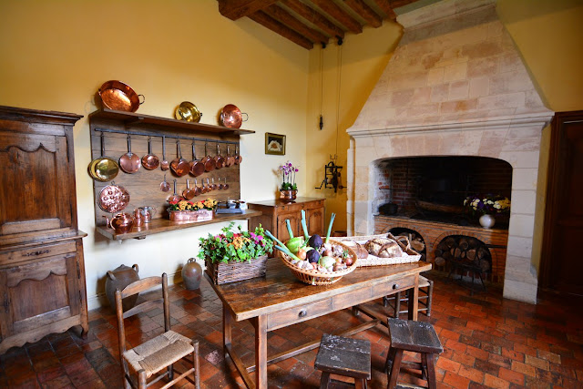 La cuisine est rustique, avec son sol en tomettes de terre cuite et l'imposante cheminée. Les ustensiles en cuivre rappellent la fonction première du lieu.