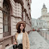 Woman in wearing a brown coat walking on side walk