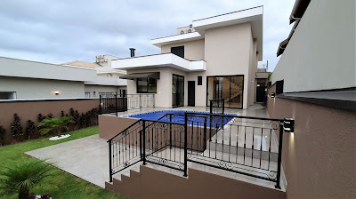 Piscina elevada sobre jardim no quintal de um sobrado construído com esmero.