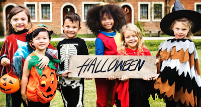 Six children in Halloween Costumes holing up a sign that says Halloween