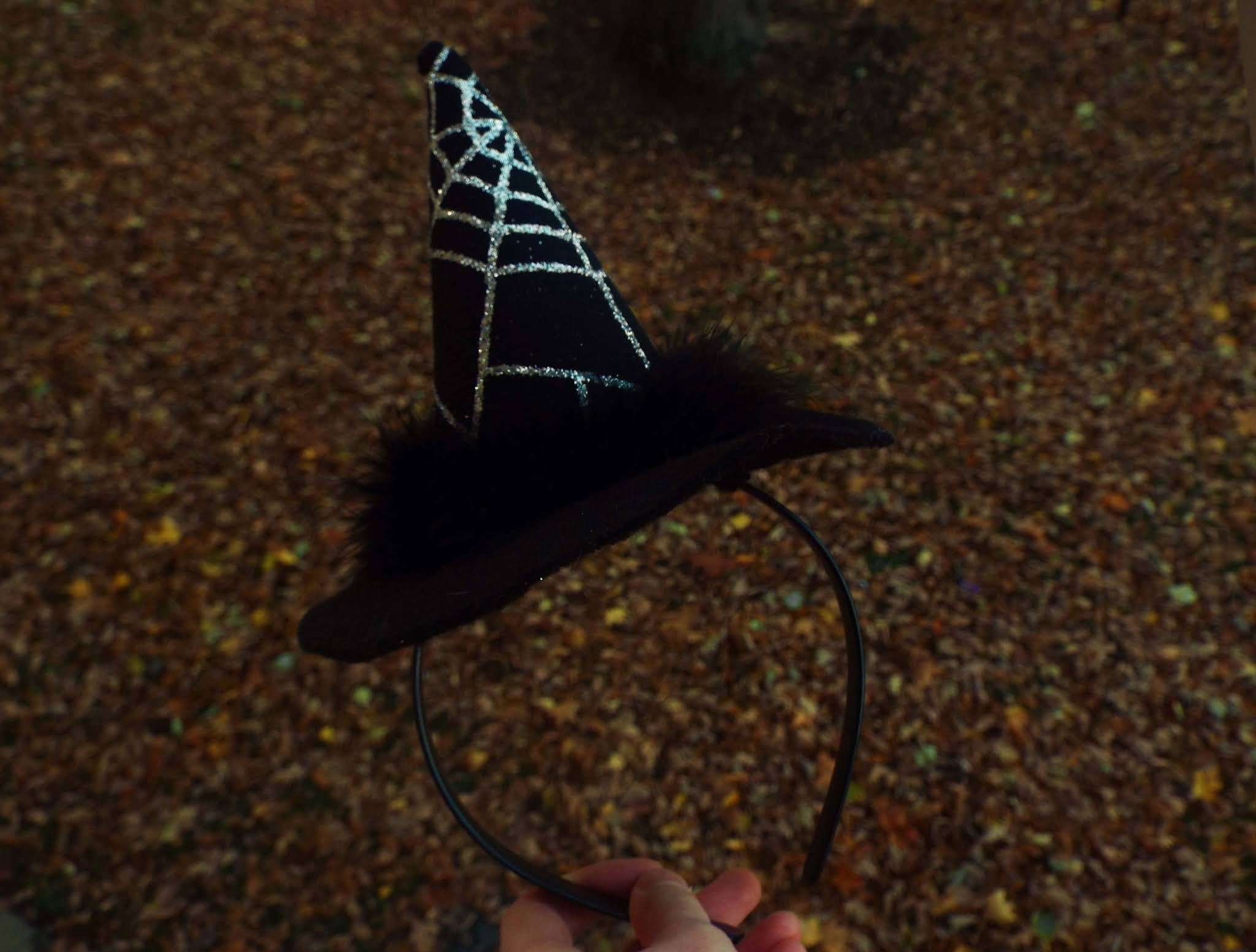 Witches hat held out in Autumnal, golden, leafy backdrop, symbolising my Hallotober Tag.