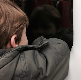 Boy looking out a window into the black