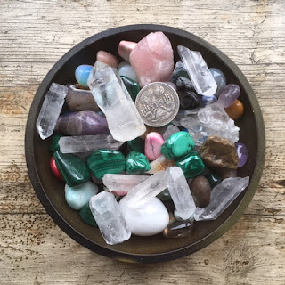 Brown bowl full of coloured crystals and a divination coin