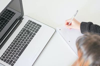 mulher escrevendo em mesa com computador