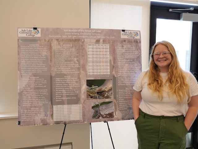 A student standing next to her research poster