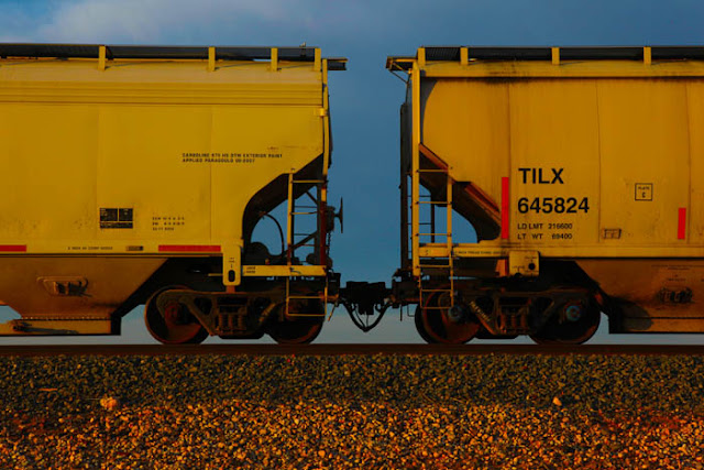 Yellow train cars on a long train traveling on the west Texas railroad.