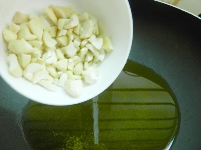 A view of cashew nuts frying in ghee until they turn light brown and become crunchy.