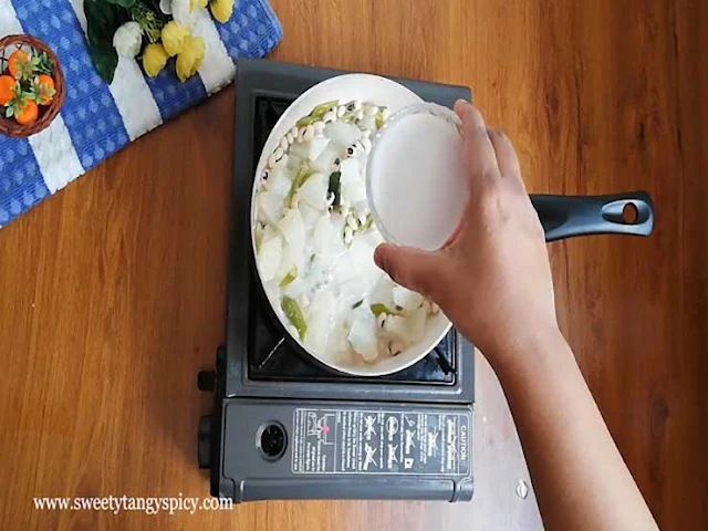 Adding first coconut milk to the simmering curry for creaminess.