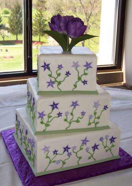 Purple and green square wedding cake with purple stars and tulips