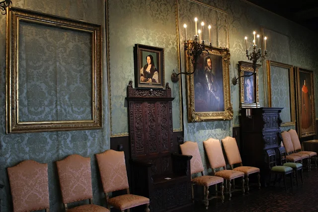 '"Alt="En la foto se ve un ángulo de una de las salas del Museo Isabella Stewart Gardner de Boston donde hay cuadros en las paredes y entre ellos marcos vacíos de los cuadros que robaron además de sillas para sentarse a contemplar las obras".